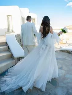 Bride and groom walking hand in hand by the sea.