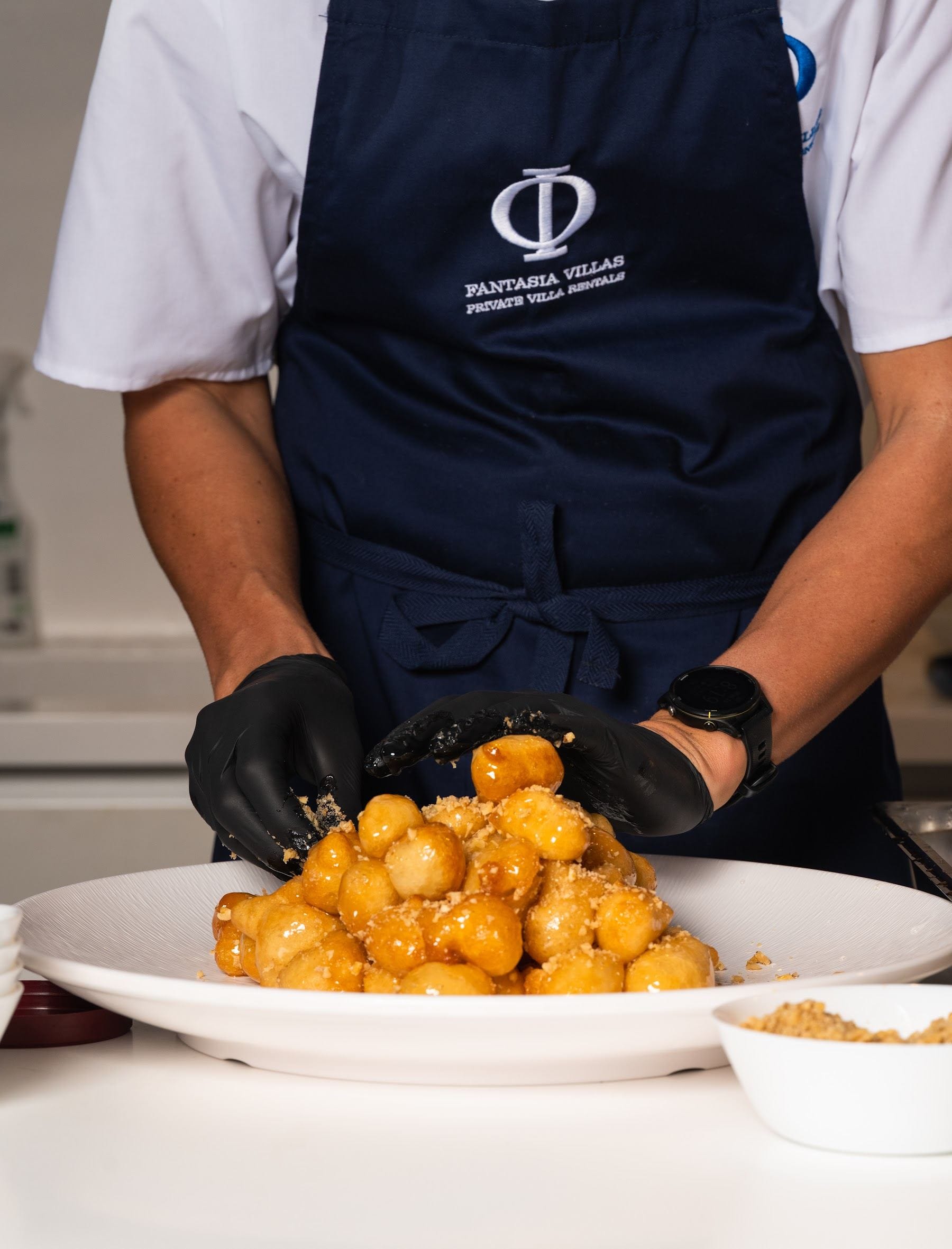 Branded apron over a plated dessert of golden pastry pearls
