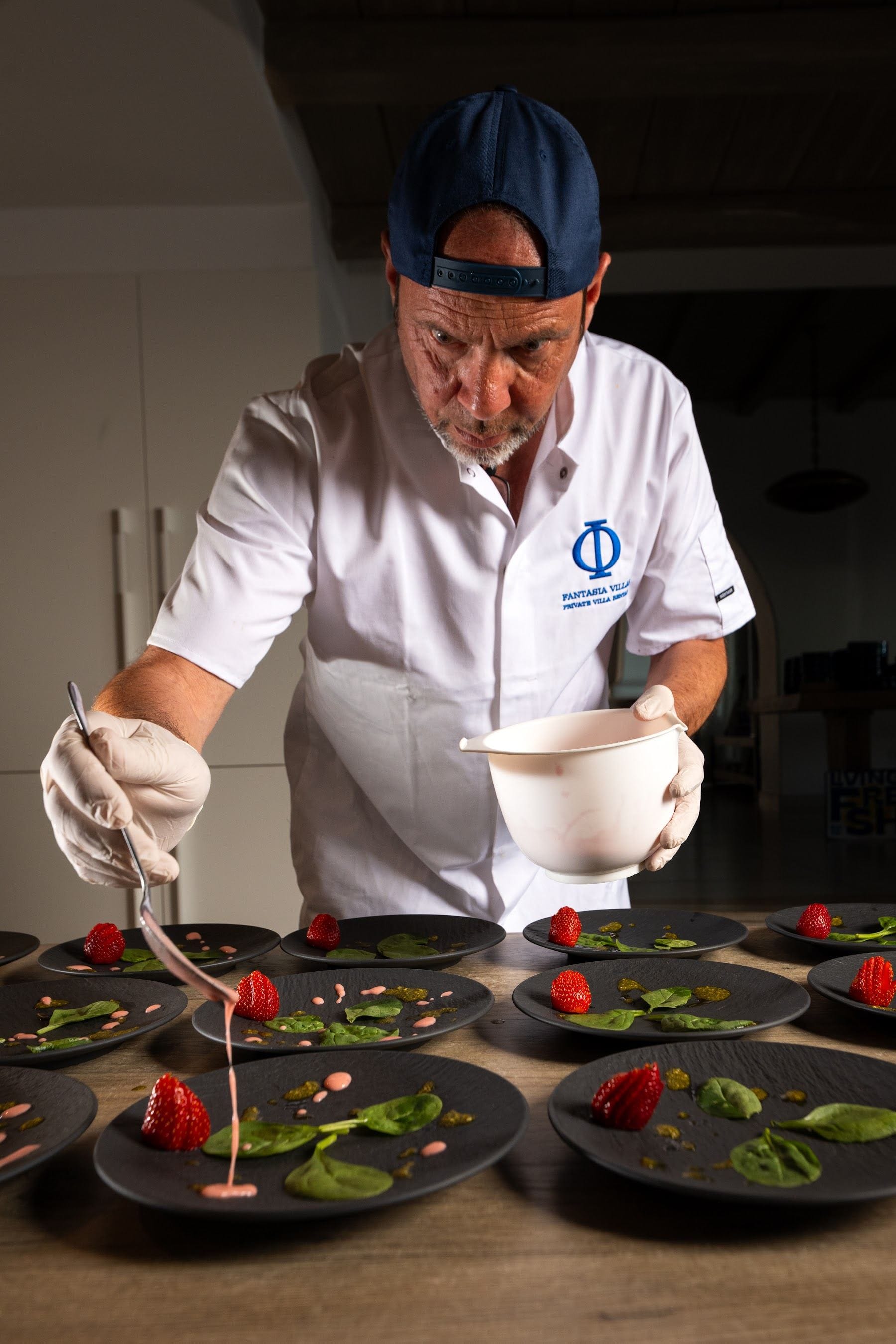 Hands finishing a dish, monogram visible on the cuff