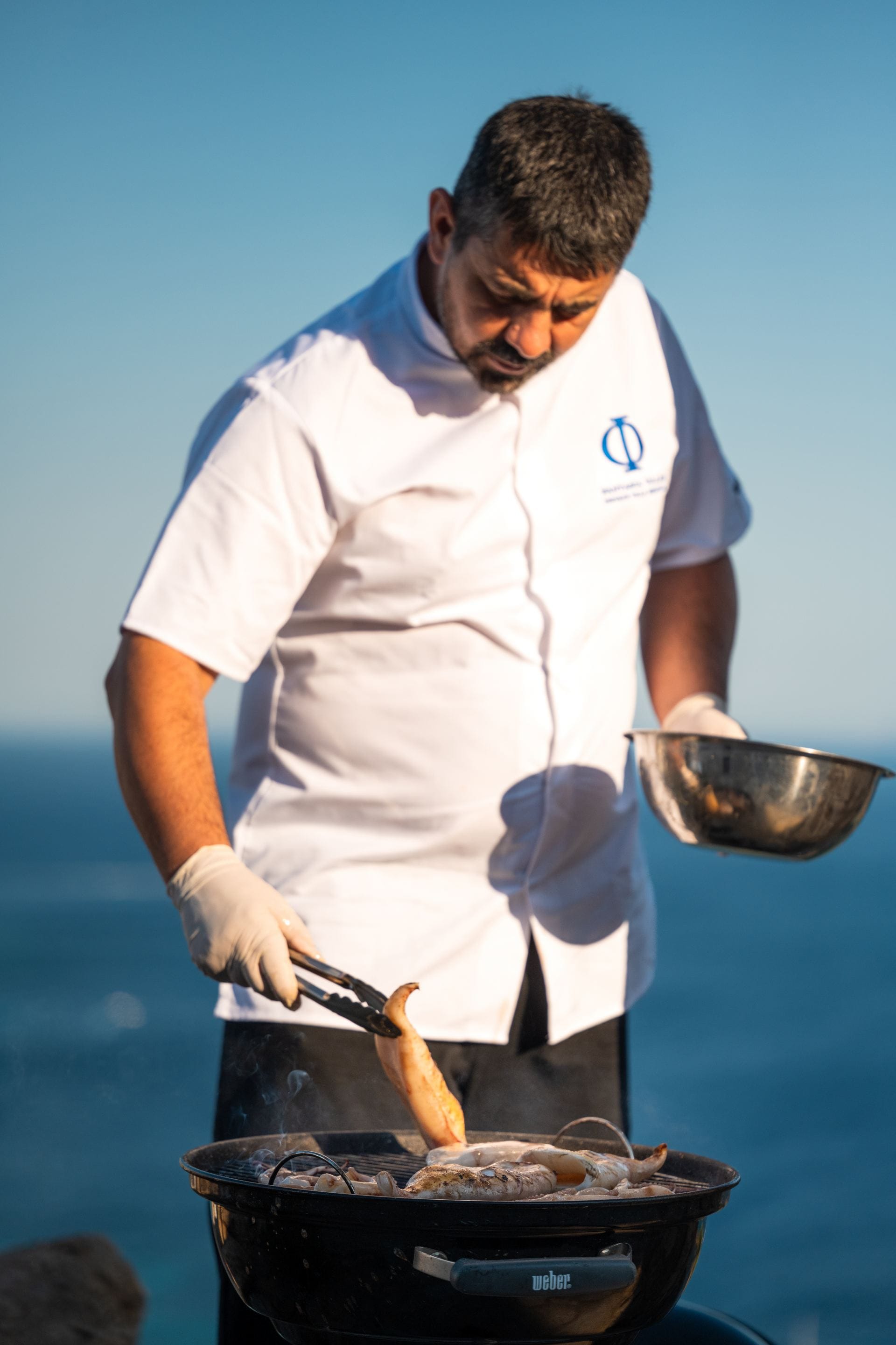 Fantasia Villas chef grilling fresh seafood overlooking the sea.