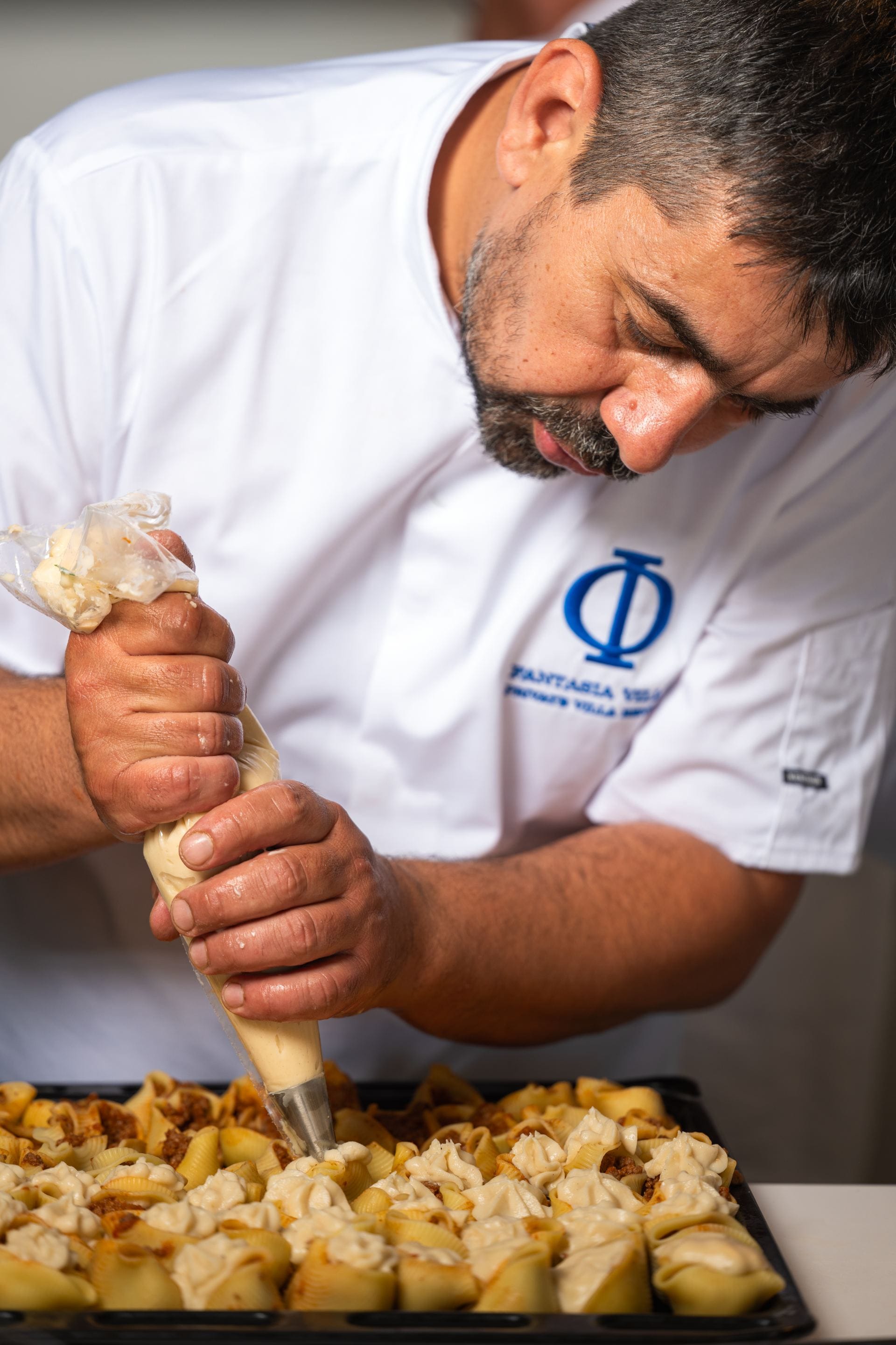 Fantasia Villas chef piping a creamy filling into pasta shells.