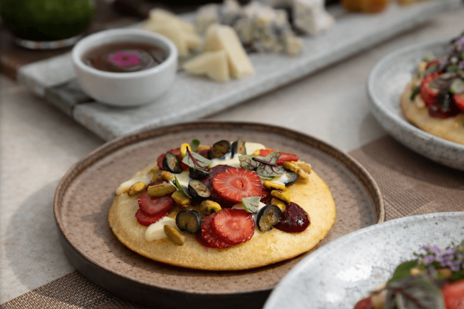 Pancakes with mixed fruits, crème anglaise, and strawberry jam, served with a selection of cheeses accompanied by red berry and apricot jam.